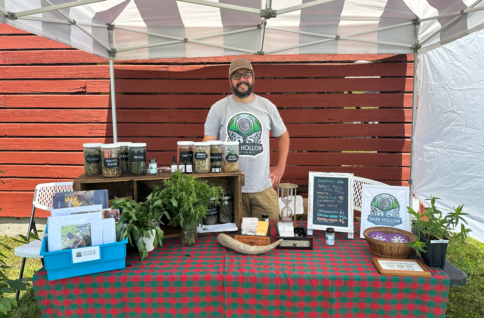 Allen Clements stands behind a table at a Horn Farm Center event with various farm items available for sale on the table.